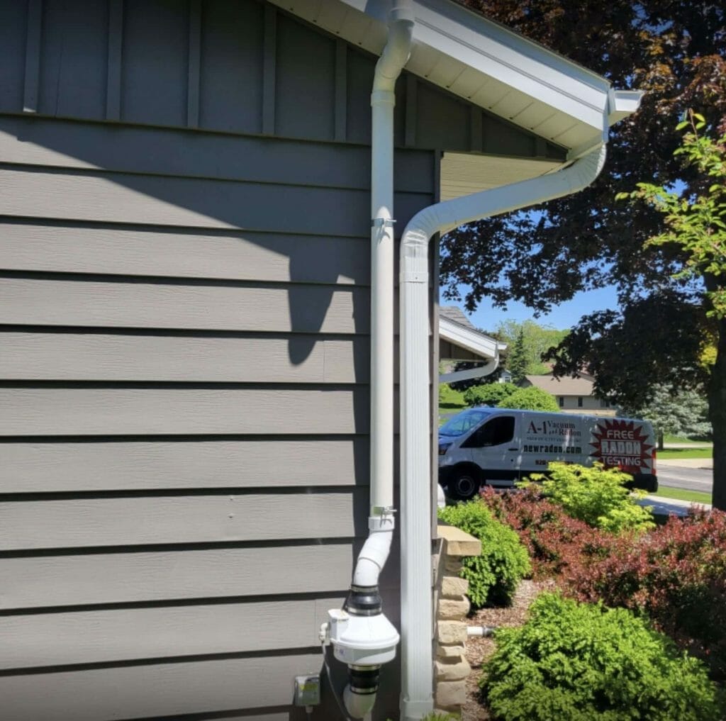 Radon mitigation system expertly installed at a local home, with visible vent pipe and fan ensuring safe removal of radon gas